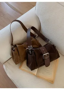 Détail de sacs bandoulière en daim vintage en caramel et café avec boucle métallique