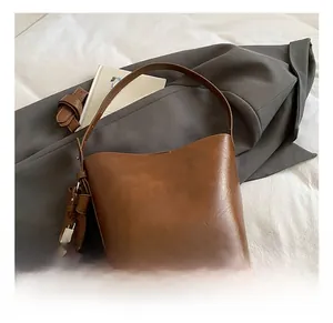 Detailed shot of brown faux leather bucket bag featuring a decorative metal lock charm