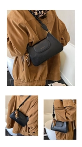 Detail of black PU leather shoulder bag with golden logo and wooden bead tassel decor