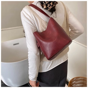 Detailed side view of the burgundy vintage bucket bag with wide strap and silver zipper
