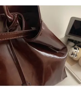 Detail of soft vintage dark brown leather tote bag with glossy texture and smooth finish