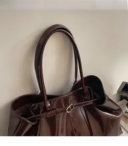 Close-up of chocolate brown leather tote featuring shiny finish and golden metal buckle