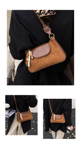 Close-up of brown suede hobo bag with ethnic beaded charm and retro gold lettering detail