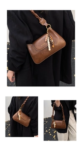 Brown vintage leather crossbody bag featuring colorful beaded charm and braided strap detail