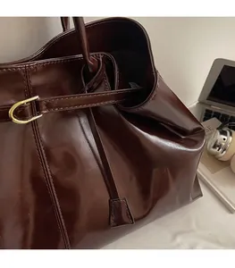 Detail of dark brown leather tote bag with glossy finish and metal buckle for commute