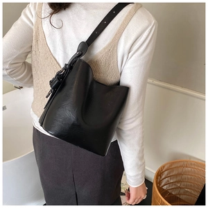 Detail showing smooth matte black leather texture and adjustable strap of the bucket bag