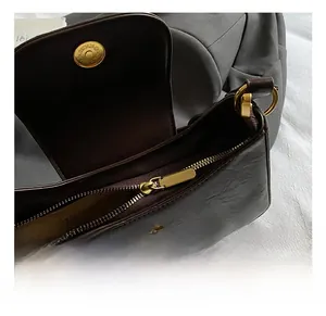 Macro detail of dark brown pebble leather bag with gold magnetic buckle and metal zipper