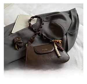 Detail of dark coffee leather handbag with woven handle, wooden beads, and shoulder strap