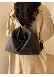 Détail du sac fourre-tout en cuir marron à double sangle sur manteau beige polyvalent