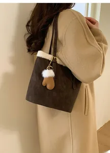 Detailed view of brown suede shoulder bag with white faux fur trim and glove charm accessory