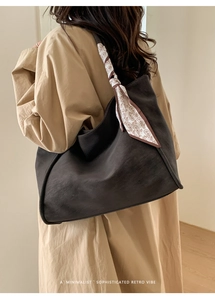 Detail of a large brown hobo bag featuring an elegant paisley scarf on the strap
