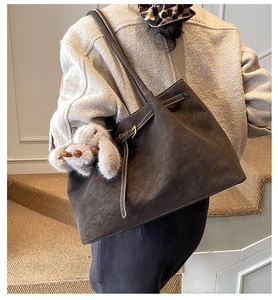Detail of dark brown suede tote bag with white contrast stitching and bunny charm