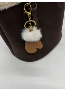 Detail of creative glove charm with brown faux suede, white plush fur and gold keychain