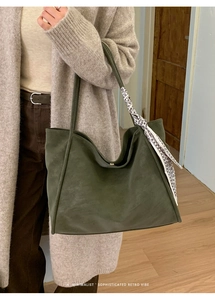 Detail of dark green suede tote bag featuring a decorative patterned silk scarf handle