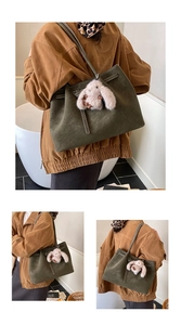 Detail of olive green suede tote bag featuring a cute white plush bunny charm accessory