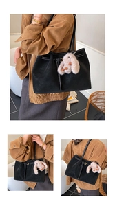 Detail of black matte tote bag featuring contrast white stitching and cute bunny pendant