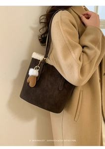 Detail of dark brown faux suede bucket bag with white fleece trim and glove charm accessory