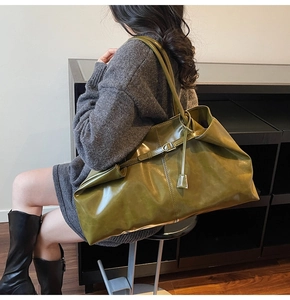 Detailed view of an olive green leather tote bag with glossy finish and buckle hardware