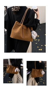Detailed view of caramel suede tote bag featuring slim straps and plush rabbit charm