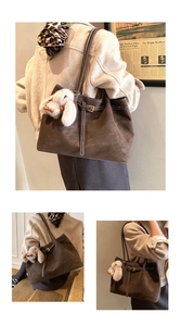 Detail of dark brown suede tote bag with a white plush bunny charm and shoulder strap