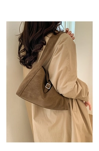 Detail of silver square buckle and brown suede texture on minimalist shoulder bag