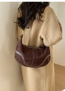 Vue détaillée du sac demi-lune en daim marron foncé porté par un mannequin