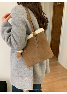 Detail of retro brown suede bucket bag with white plush trim and golden metal buckles