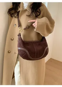 Détail du sac demi-lune en daim marron avec surpiqûres blanches et garnitures dorées