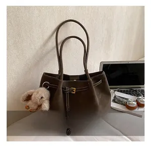 Detail of dark brown suede tote bag with decorative buckle and elephant plush charm