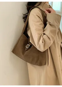 Detail view of a large brown suede tote bag featuring a buckle closure and soft texture