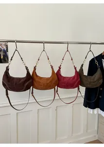 Gros plan sur quatre sacs hobo rétro en daim aux tons café, caramel, bordeaux et vert
