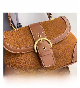 Close-up of leopard print fabric texture with brown leather trim and gold buckle detail