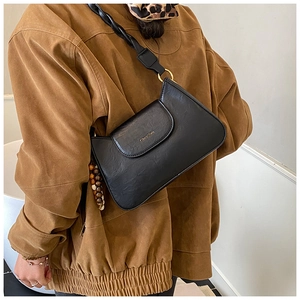 Detailed view of black vintage leather crossbody bag with braided strap and gold accents