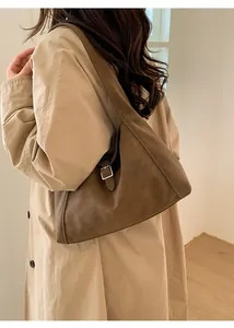 Close-up of vintage brown suede hobo bag shown from side profile on shoulder