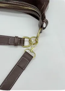 Détail du sac marron foncé avec coutures blanches contrastées et boucle en métal doré