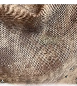 Vue macro du tissu sergé métallisé marron avec rivets sur un grand sac fourre-tout