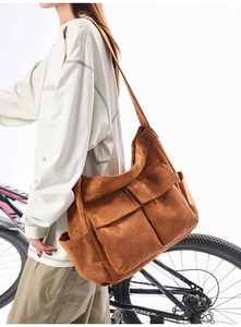 Detail of a large brown utility shoulder bag with multiple functional pockets and soft texture