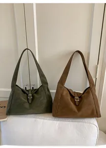 Detail of vintage olive green and brown suede tote bags with metal buckle straps