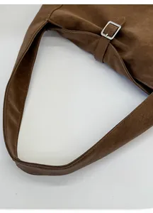 Detail of dark brown suede shoulder bag with adjustable silver metallic buckle