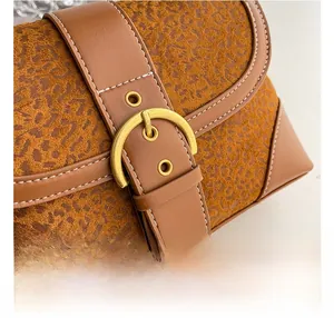 Close-up of leopard print leather handbag featuring golden horseshoe hardware and white stitching