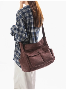 Detail of dark brown corduroy shoulder bag with multi-pocket utilitarian design