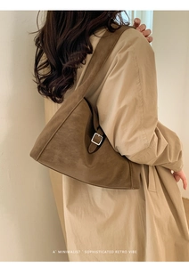 Detail view of a vintage dark camel suede underarm bag with adjustable metal buckle strap