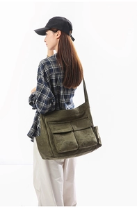 Detail view of large dark green canvas shoulder bag with functional exterior flap pockets