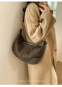 Détail du sac hobo en daim marron foncé avec des coutures contrastantes blanches élégantes