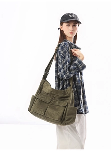 Detailed side view of olive green canvas shoulder bag worn by model in studio