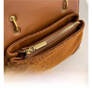 Detailed close-up of smooth gold zipper and leopard print fabric on a brown leather bag