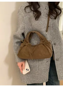 Vue détaillée d'un sac à main en daim marron avec nœuds décoratifs et bandoulière réglable