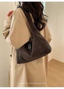 Detail of dark brown retro shoulder bag with silver hardware and suede texture finish
