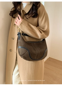 Détail du sac hobo en daim vintage avec surpiqûres contrastées et boucles en laiton