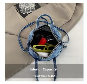 Top view of blue denim handbag interior holding smartphone, sunglasses, and lipstick